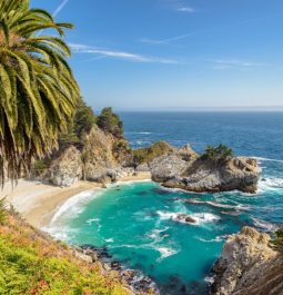 Turquoise water meets the sand at the edge of a cliff in Big Sur, California