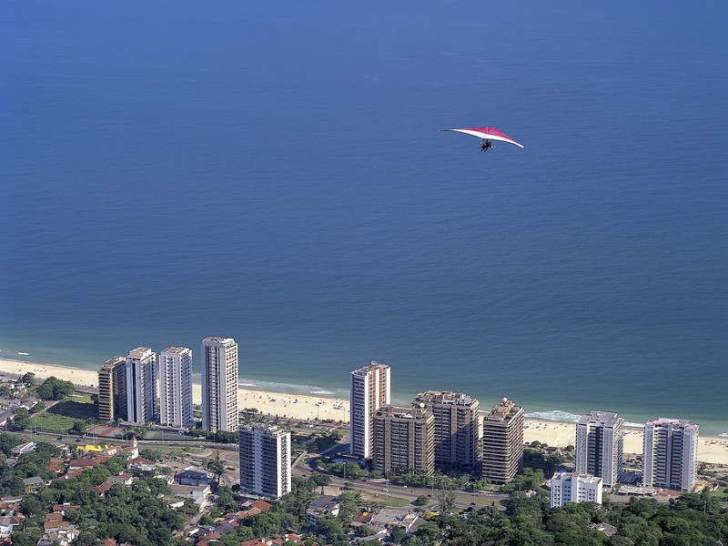 Hang glider flying over the Sao Conrado neighborhood after jumping the ramp located in Pedra Bonita