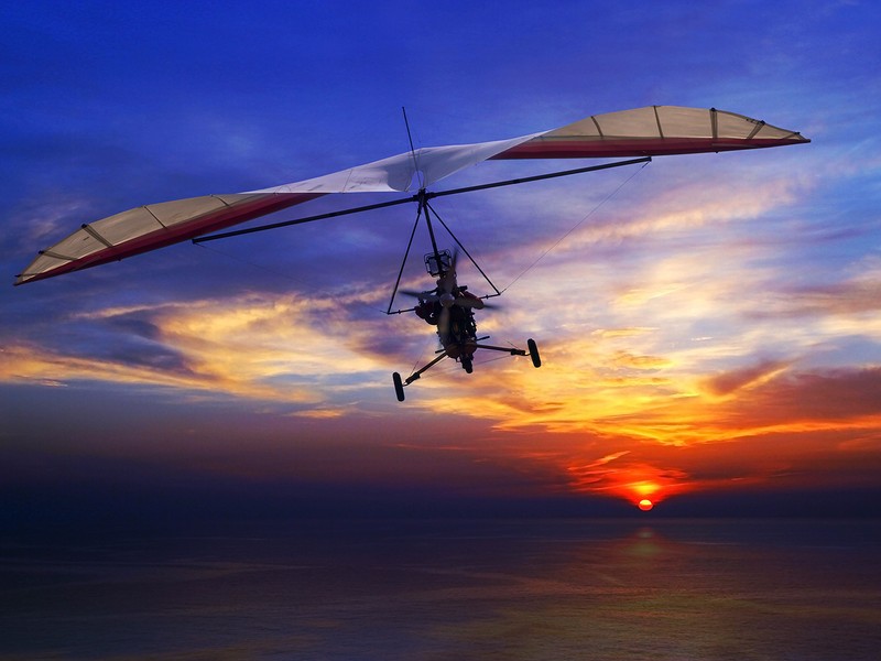 Motorized hang glider in the sunset above sea