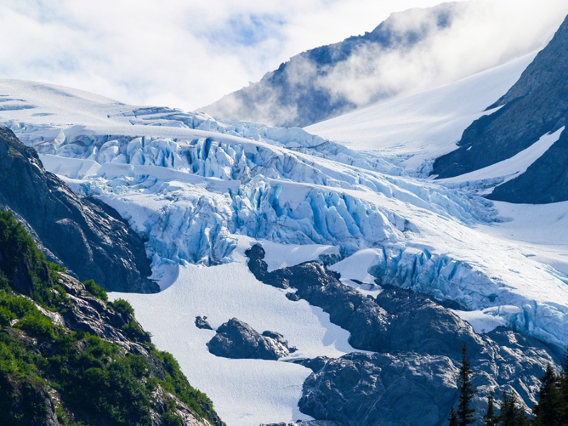 View through tree clad valley to distant Alaskan glacier in Chugach State Park