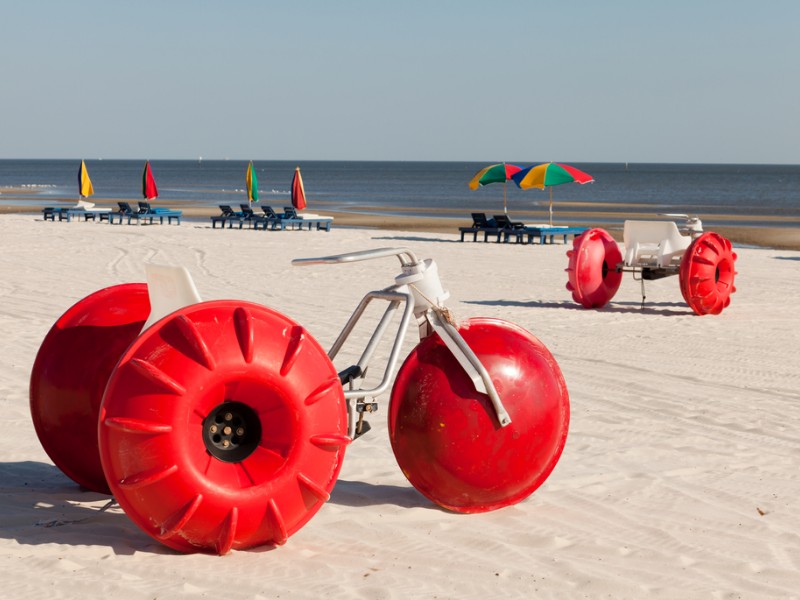 Colorful beach tricycles along the shoreline with lounge chairs and umbrellas along the Mississippi Gulf Coast