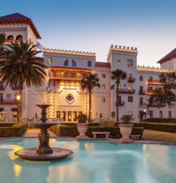 exterior of large Spanish-style resort with large fountain in front