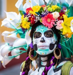 woman with painted skeleton face and flower crown for day of the dead celebration