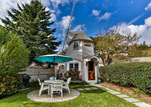 Quaint windmill turned house with table and chairs in front in the yard