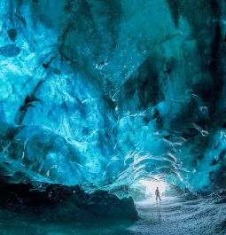 turquoise ice cave with person standing near entrance