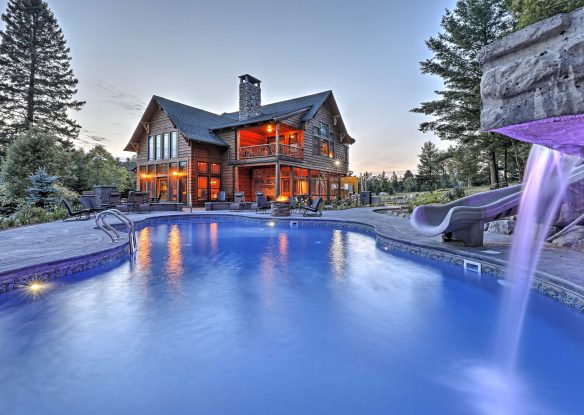 swimming pool at dusk in front of log cabin