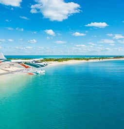 turquoise waters with small barrier island and sea plane about to land