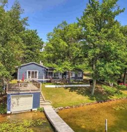 exterior of home sitting on lake surrounded by trees