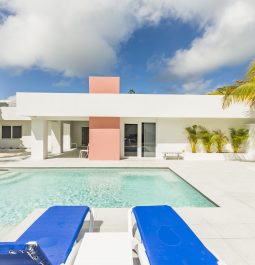 sun loungers set by a sparkling pool and white and pink building