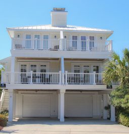 A tall beach house stands with multiple decks and a double garage