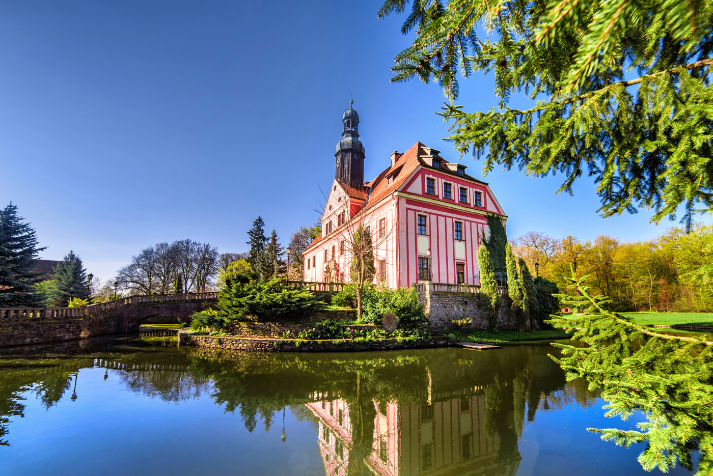 Pink toned castle sitting next to the glassy lake