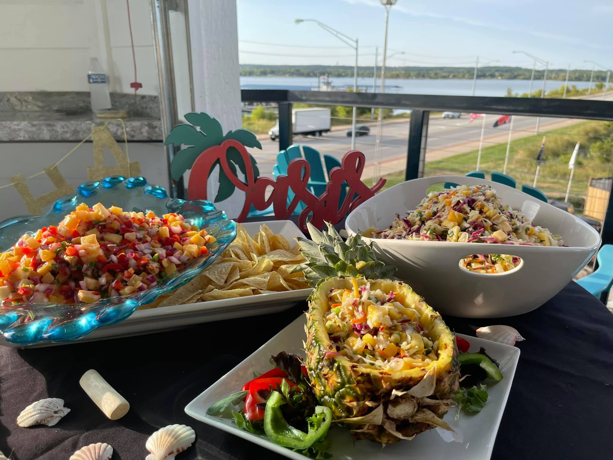 Table will tropical style food and a sign that says "Oasis"