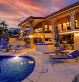 Back of stunning, large villa with stone accents and swimming pool facing Pacific