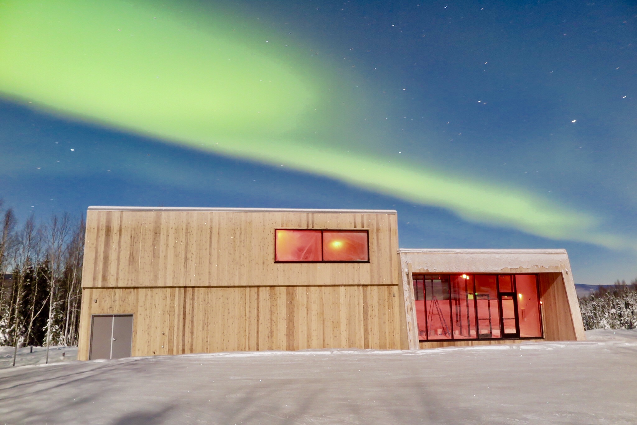 Double height modern cabin in front of the Northern Lights