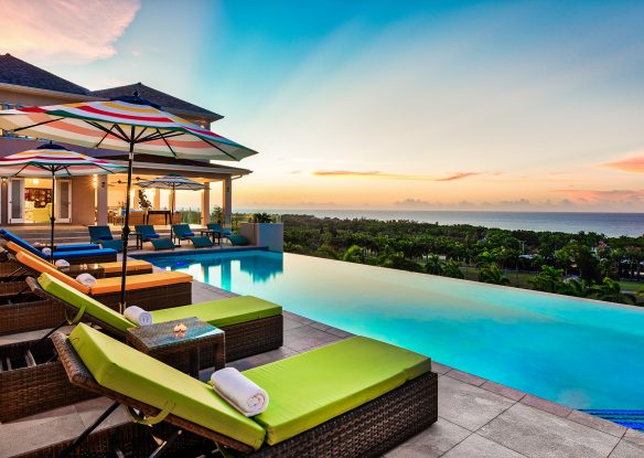 Rainbow hued sunset from infinity pool with green sunbeds