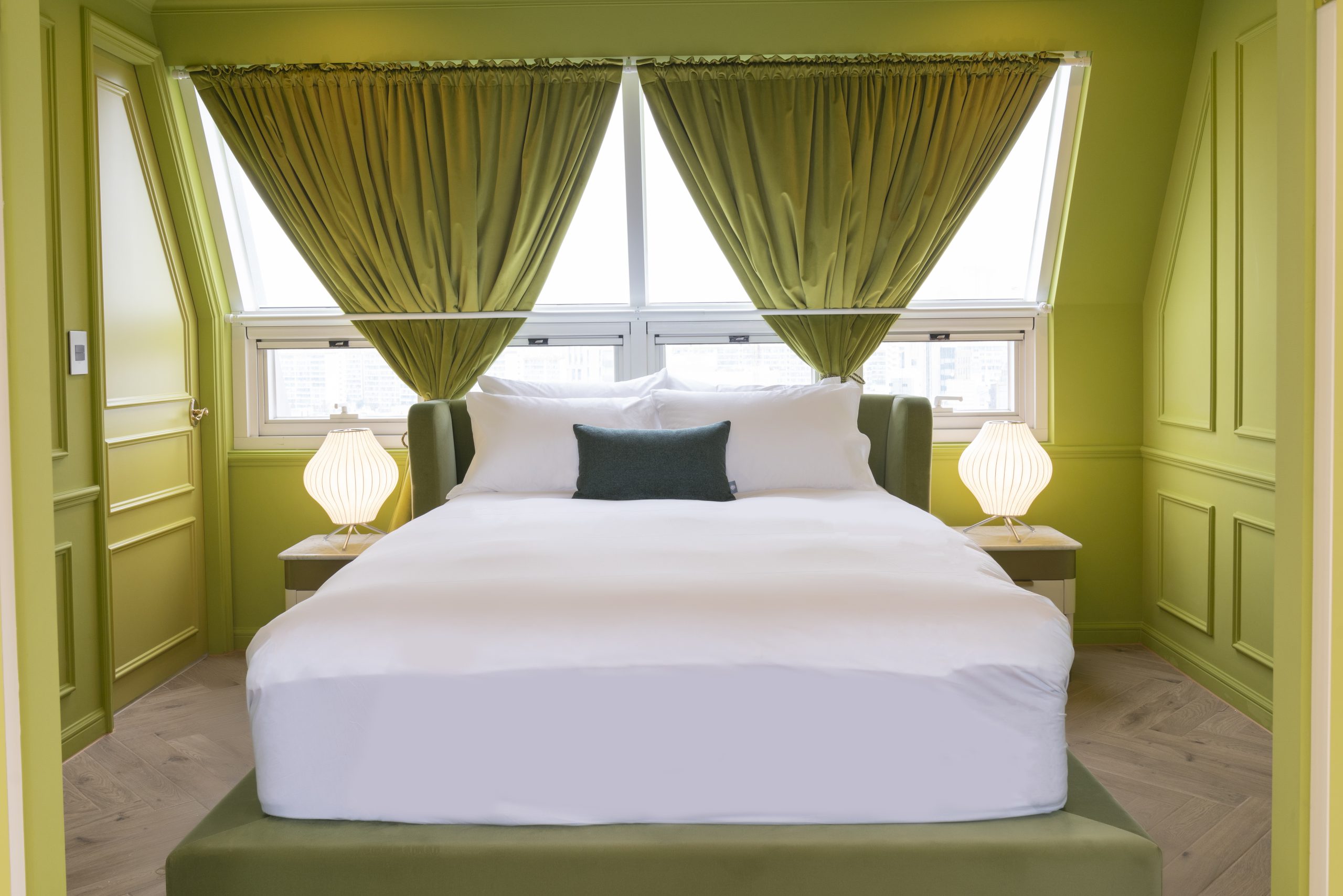 Trendy green bedroom with spacious double bed and airy lighting