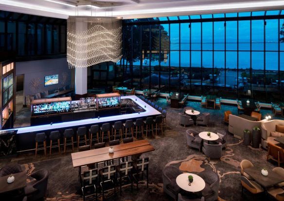 Big hotel lobby with panoramic windows overlooking a bay