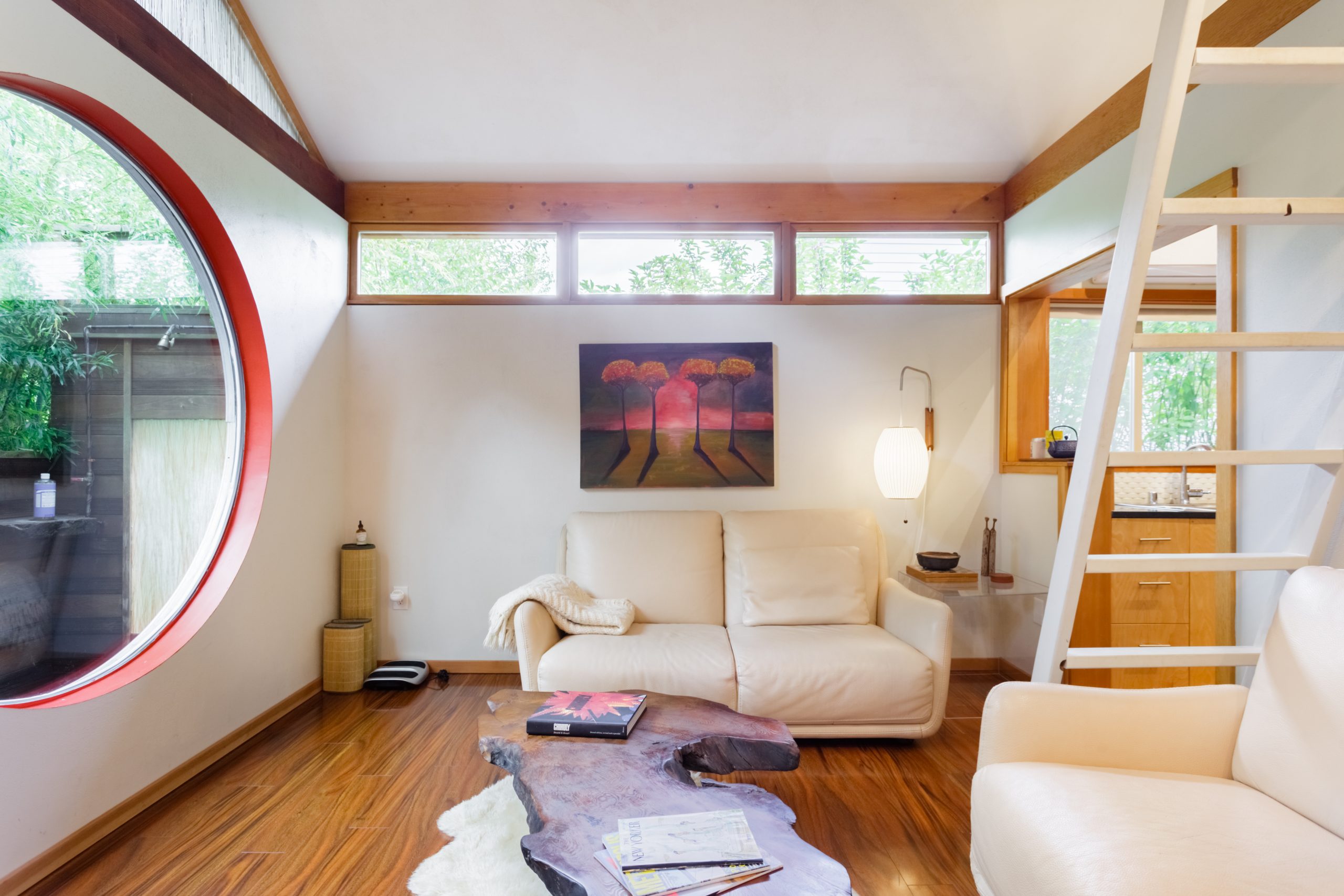 Stylish living room with huge circular mirror and stairs leading to bedroom