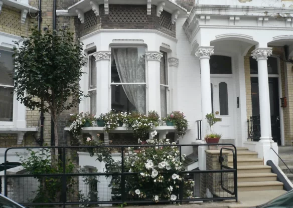 Front of London row home with fence and flowers