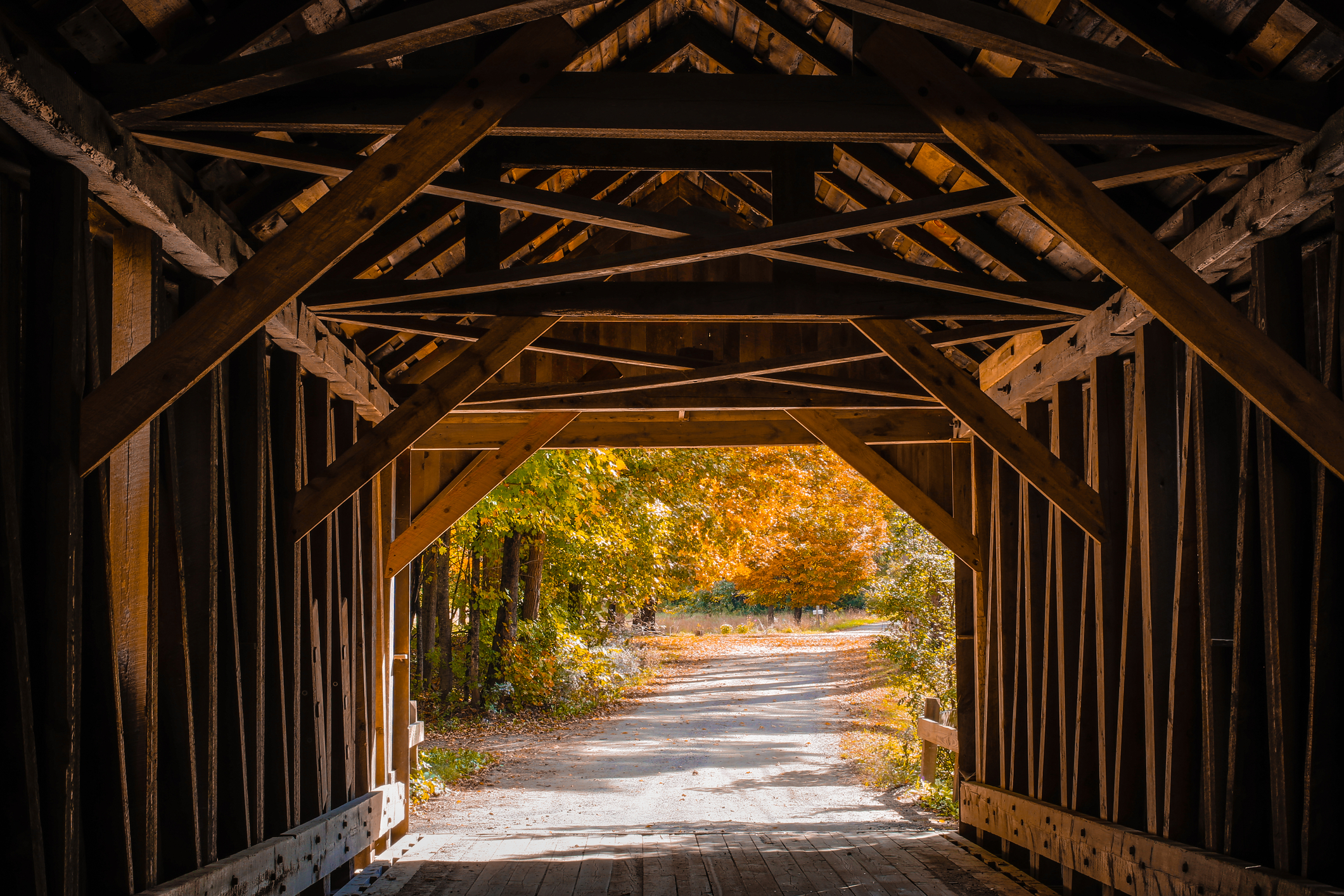 Inside the Blow Me Down Covered Bridge in Cornish, New Hampshire looking out at the colorful fall foliage