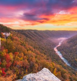 fall foliage on mountains surrounding river gorge at sunset