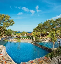 Bright blue pool surrounded by blue skies and green trees