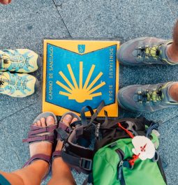 pilgrims standing around a camino marker on the sidewalk