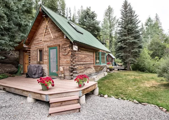 log cabin with small deck surrounded by evergreens