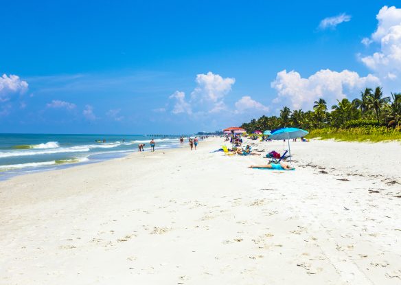 people enjoy the beautiful public white beach at Naples Pier