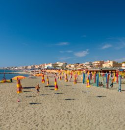 beach with folded umbrellas stuck in the sand