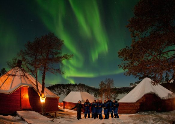 guests enjoy the unique opportunity to watch the northern lights over a snowy resort in Norway