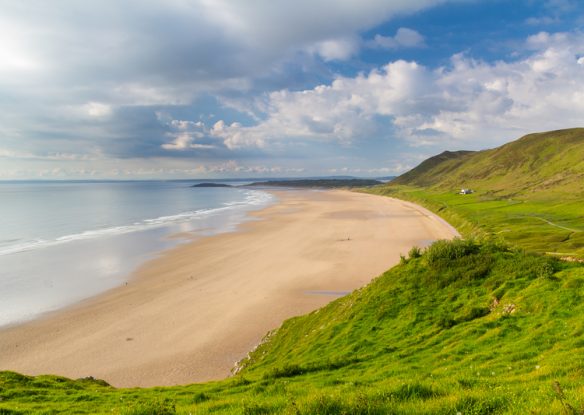 white sand beach with grassy hills nearby