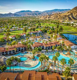 Aerial view of a resort with water park and a lazy river next to the mountains