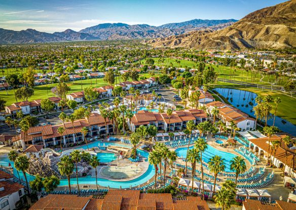 Aerial view of a resort with water park and a lazy river next to the mountains